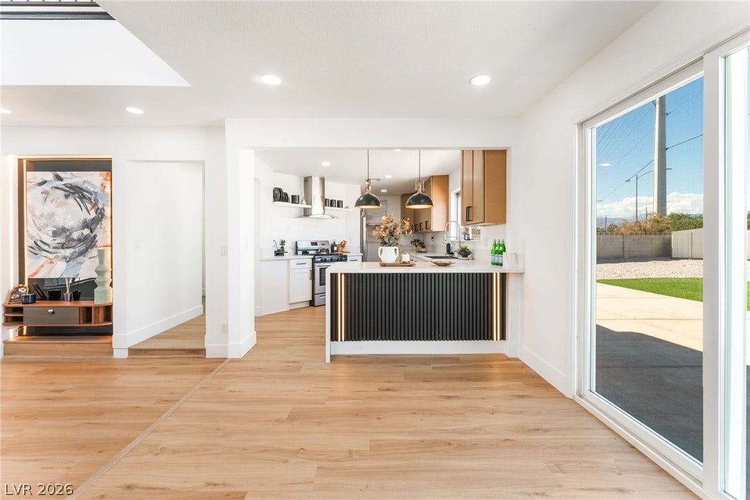 Gleaming wood floors anchor an airy, open layout flowing seamlessly toward the modern kitchen.