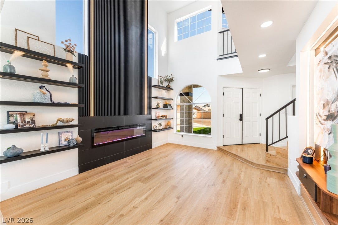 Dramatic two-story ceilings and a modern linear fireplace create a striking first impression.