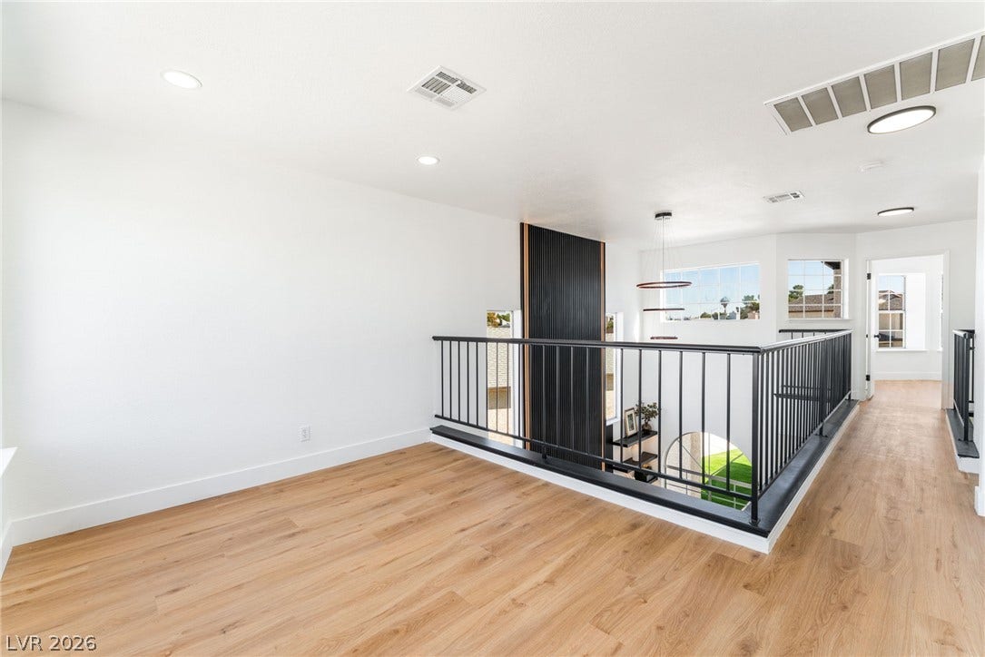 Gleaming wood floors and modern black metal railings define this airy upstairs landing overlook.