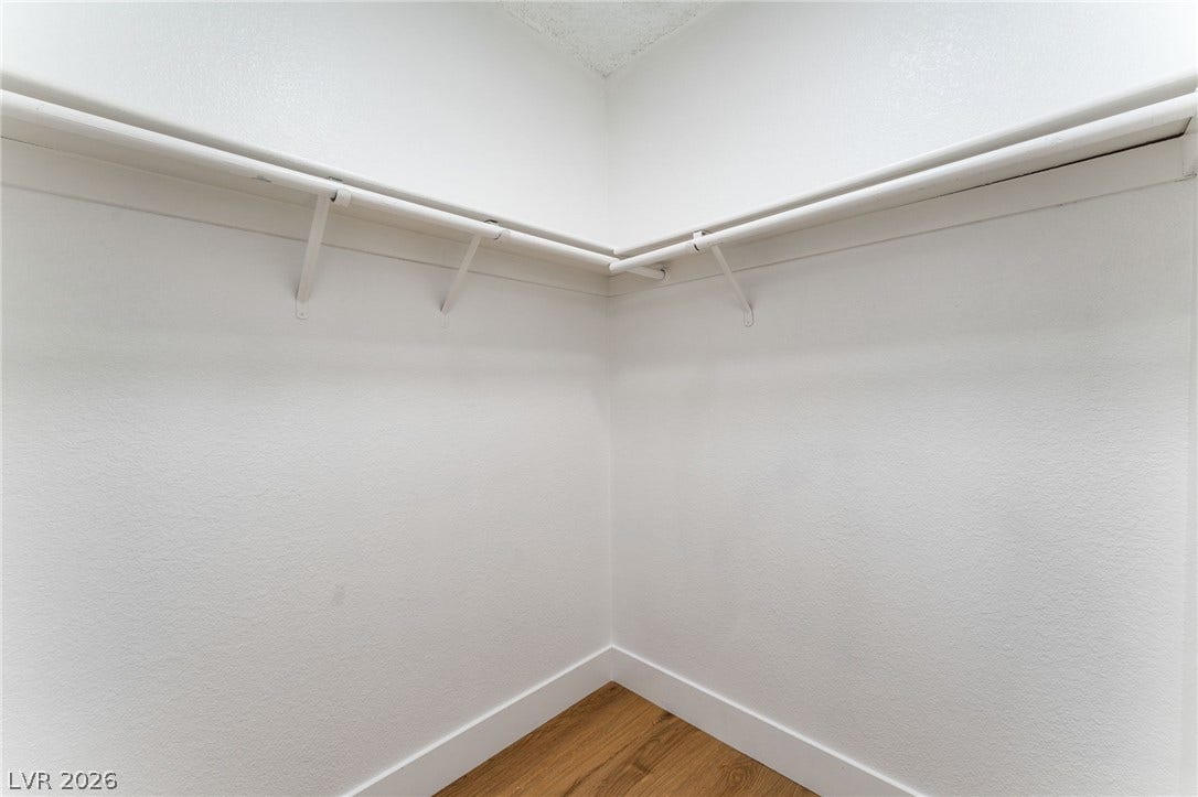 Ample closet space features hanging rods and classic wood flooring.