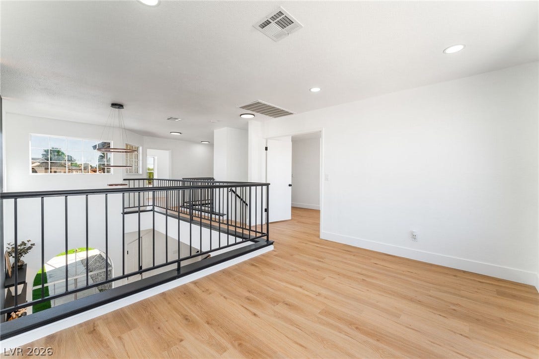 An open upper landing features smooth wood flooring and recessed lighting overlooking the foyer below.