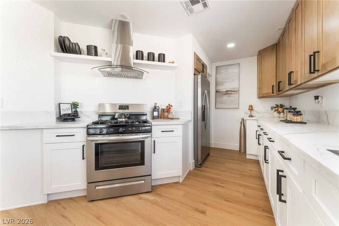 Warm wood flooring complements clean white countertops and modern cabinetry in this culinary space.