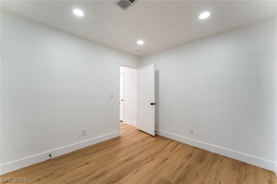 Warm wood-style flooring complements the clean white walls and recessed ceiling lighting.
