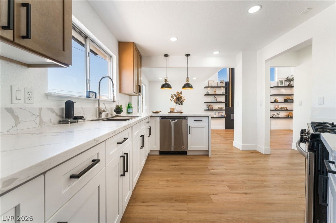 Elegant stone countertops and rich wood flooring define this open-concept kitchen.