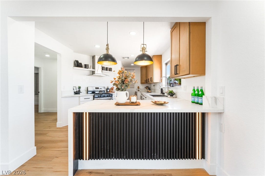 Gleaming stone countertops and warm wood floors define this updated open-concept kitchen space.