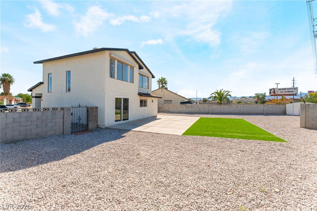 An expansive gravel yard features a concrete patio pad and low-maintenance turf grass.