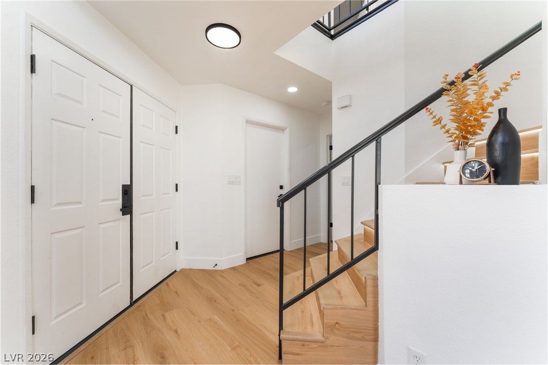 An inviting entryway leads directly to clean-lined wooden stairs with minimalist metal railings.