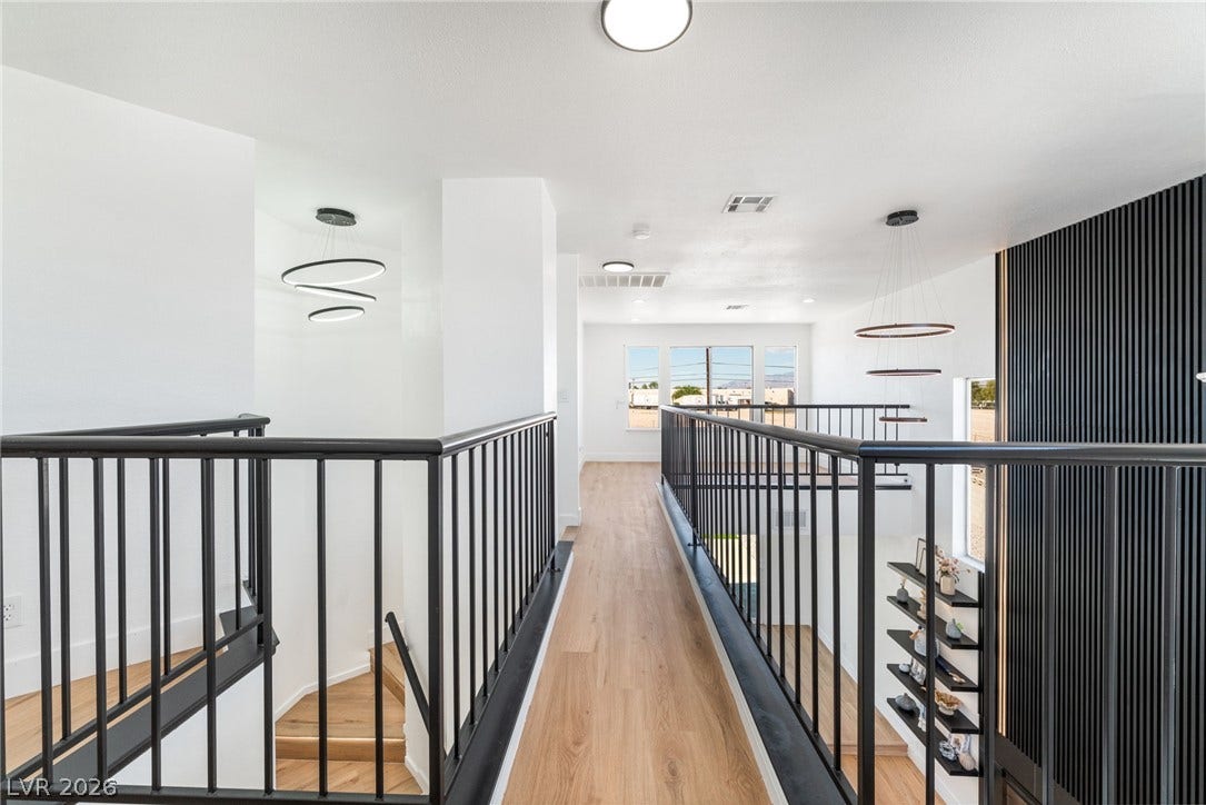 An upper-level walkway overlooks the living space below, featuring clean architectural lines and wood-toned flooring.