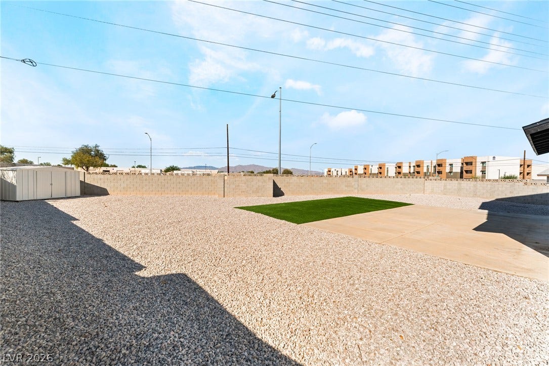 A spacious gravel yard features a concrete patio and a secure block perimeter wall.