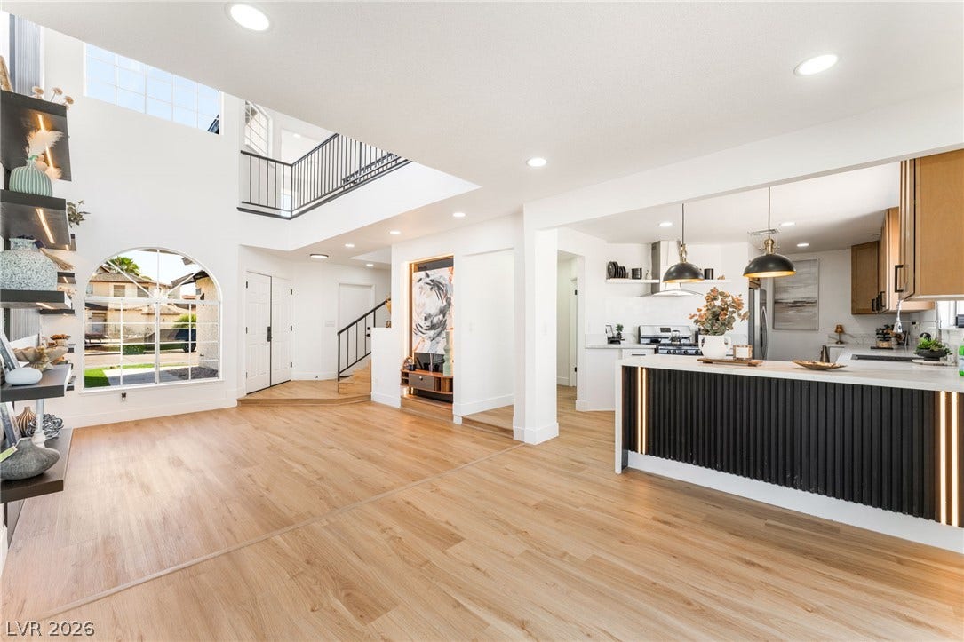 Gleaming wood floors anchor a dramatic soaring entryway and a sleek modern kitchen.