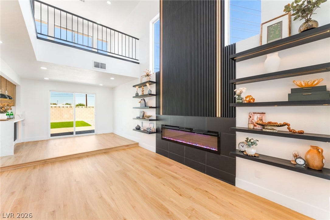 Soaring ceilings and a dramatic fireplace wall define this light-filled modern living space.
