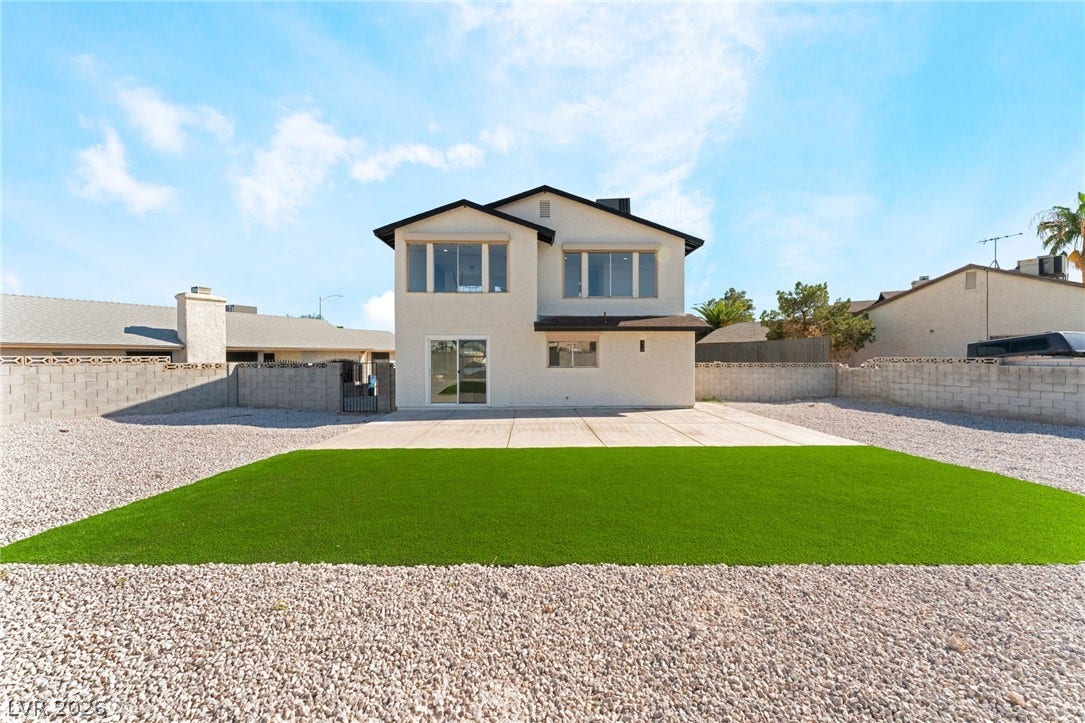 A spacious backyard patio borders a low-maintenance lawn under clear desert skies.