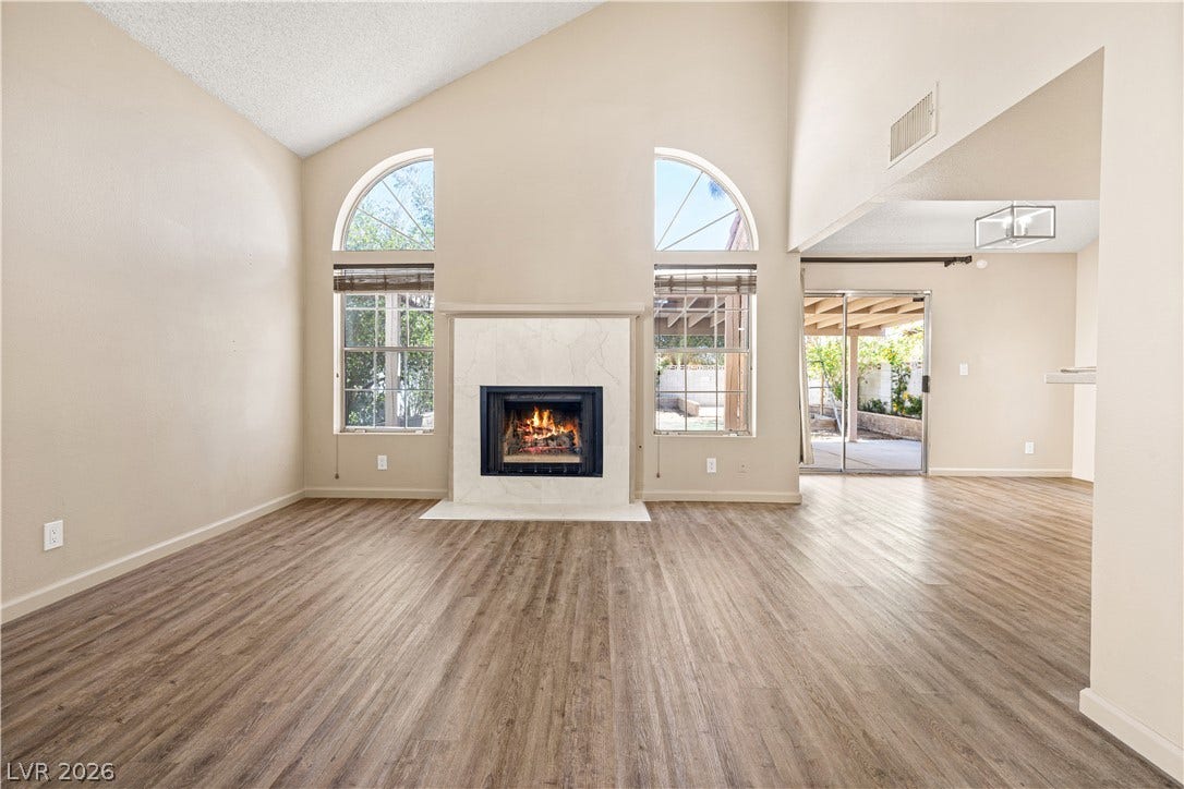 325 Manor Street, Las Vegas, NV 89145 Vaulted ceilings and a central fireplace anchor this welcoming open-concept living area.