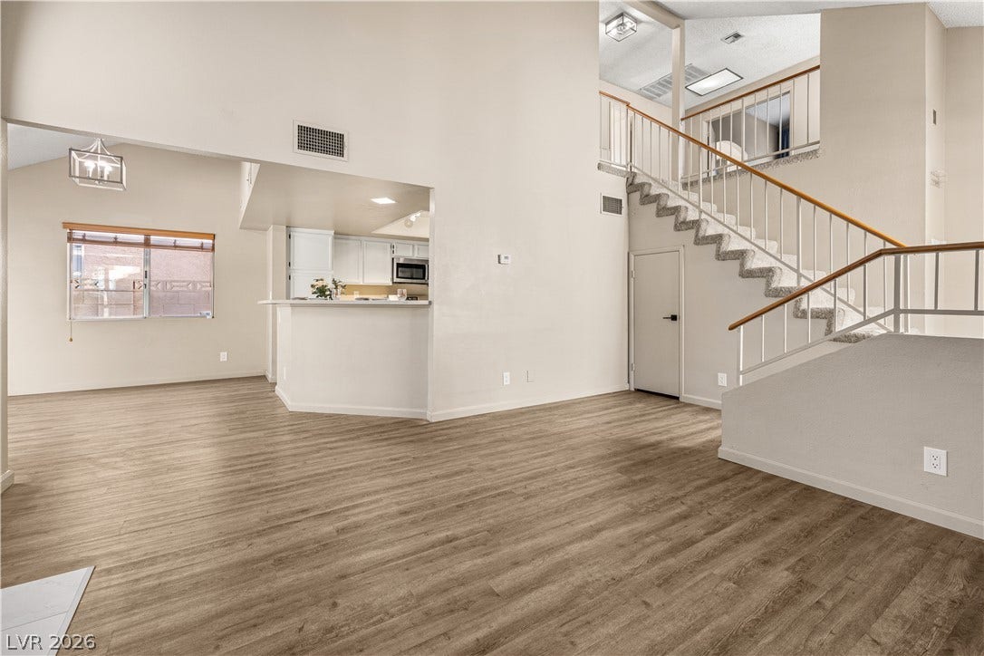 325 Manor Street, Las Vegas, NV 89145 High ceilings and a prominent staircase define this airy open-concept living space with wood flooring.