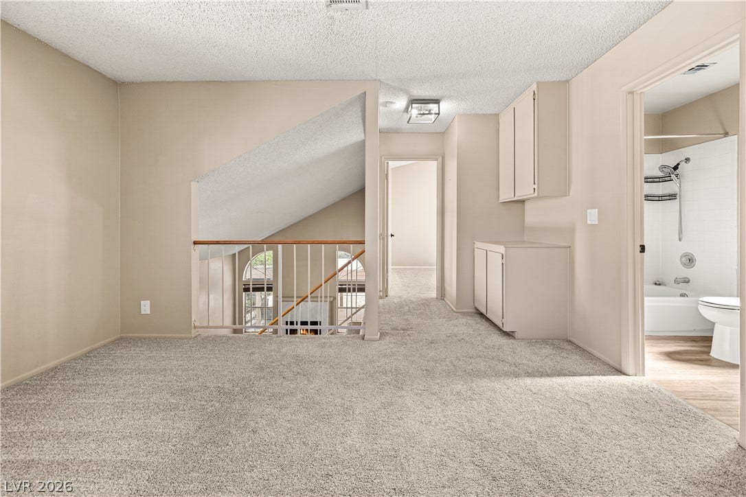 325 Manor Street, Las Vegas, NV 89145 An upper-level loft area features wall-to-wall carpeting and built-in hallway cabinetry next to a bathroom.