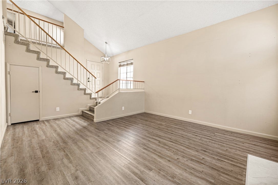 325 Manor Street, Las Vegas, NV 89145 An open living space features soaring vaulted ceilings, durable wood-look flooring, and a prominent staircase.