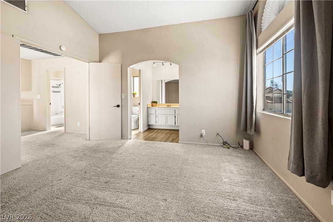 325 Manor Street, Las Vegas, NV 89145 High vaulted ceilings and neutral carpeting define this airy primary suite with an attached bathroom.