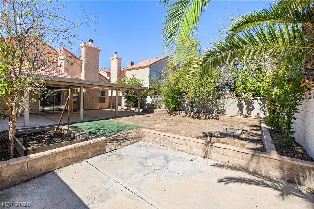 325 Manor Street, Las Vegas, NV 89145 A spacious backyard area includes a covered concrete patio and stone planter beds.