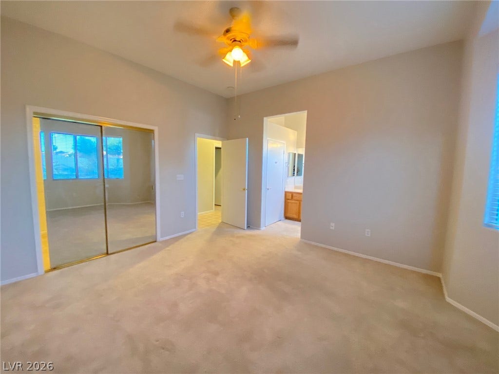 A spacious bedroom features neutral carpet and a large sliding mirrored closet.