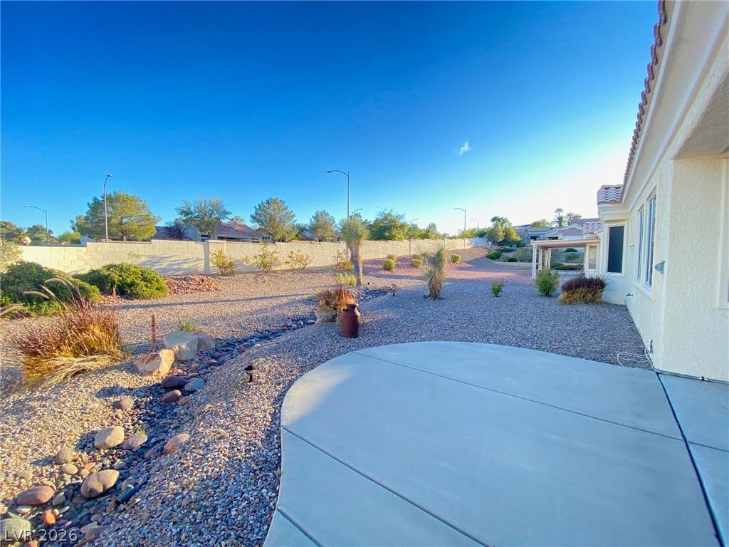 A spacious concrete patio overlooks the low-maintenance desert landscaping and expansive block wall fencing.