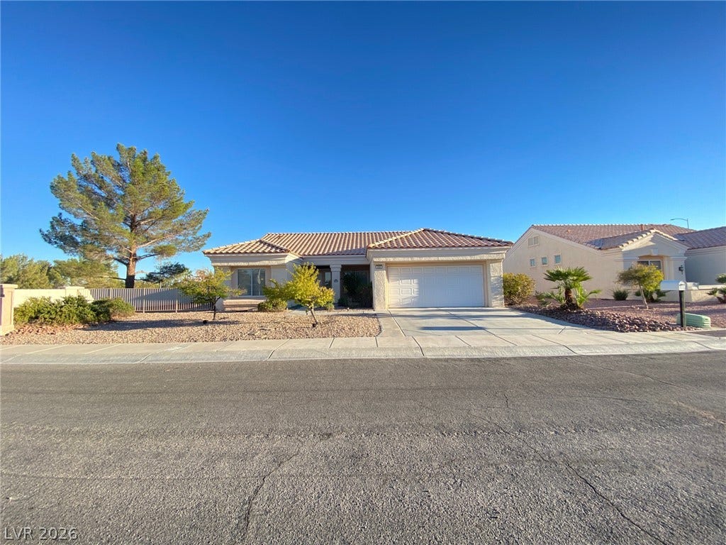 Classic desert landscaping accents this single-story home featuring a tile roof and two-car garage.