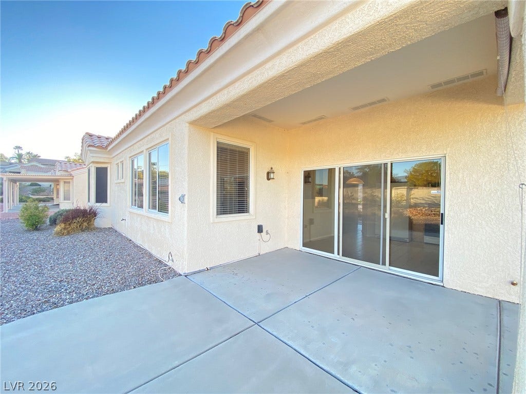 A spacious covered concrete patio transitions smoothly to the gravel yard through sliding glass doors.