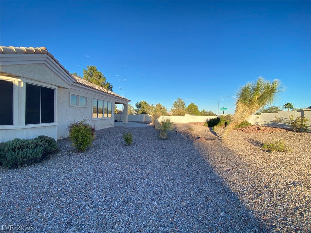 Low-maintenance desert landscaping surrounds this stucco home under clear blue skies.