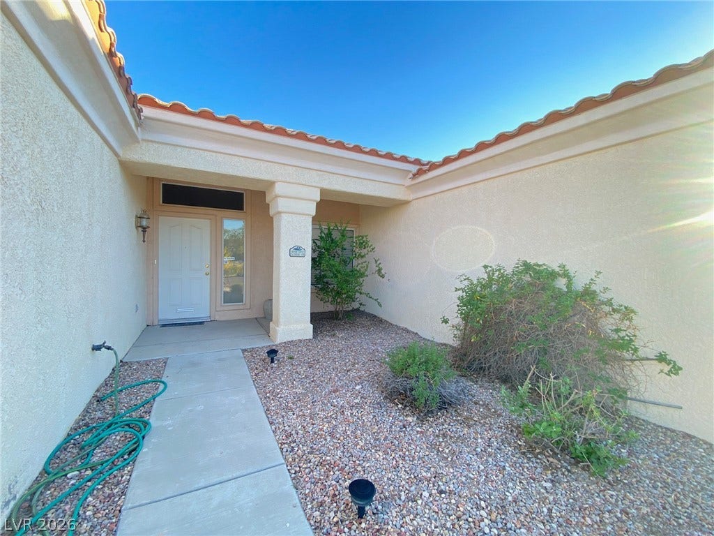 A welcoming front entry features a concrete walkway leading past low-maintenance desert landscaping.