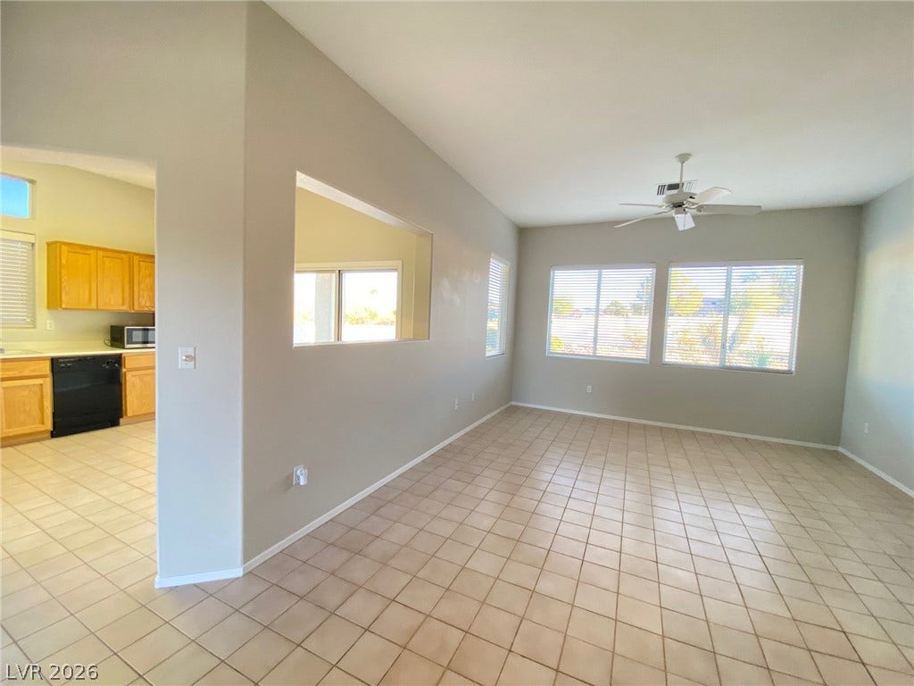 Tiled flooring flows through an open living area featuring a pass-through wall to the kitchen.