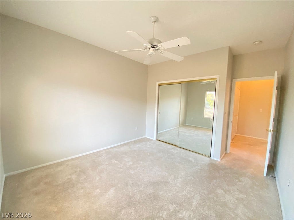 Plush carpeting anchors this spacious bedroom featuring a mirrored closet and clean architectural lines.