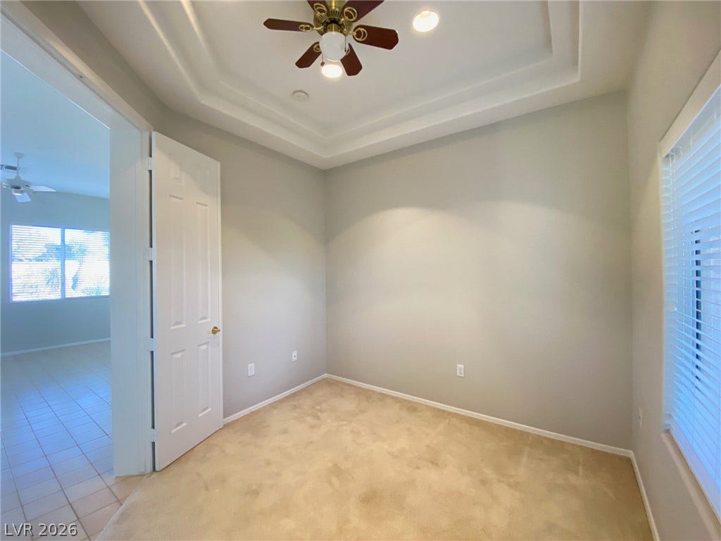 Plush carpeting and a classic tray ceiling define this versatile, light-filled interior space.