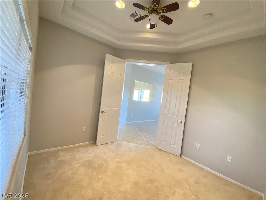Double doors open from a carpeted room featuring a classic tiered ceiling design.
