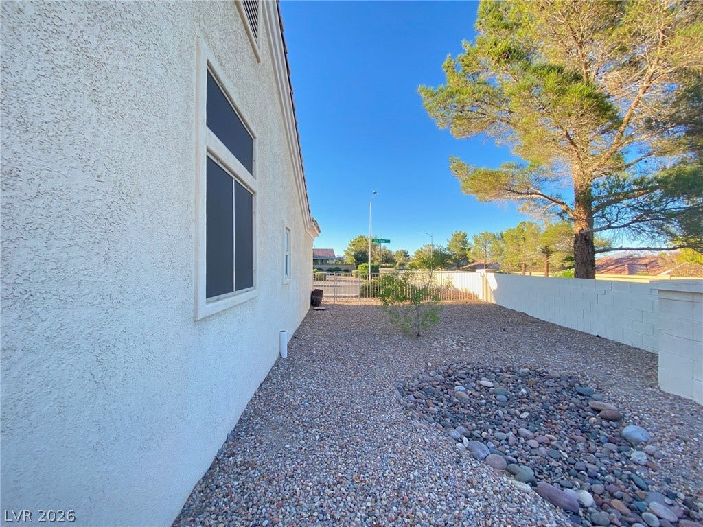 Low-maintenance gravel landscaping lines the exterior side of this classic stucco home.