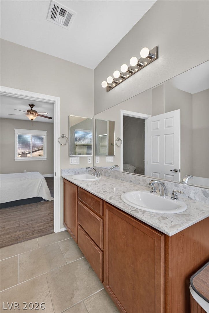 8112 Winterfell Place, Las Vegas, NV 89166 Double vanity highlights this clean bathroom setup featuring durable tile flooring and stone countertops.