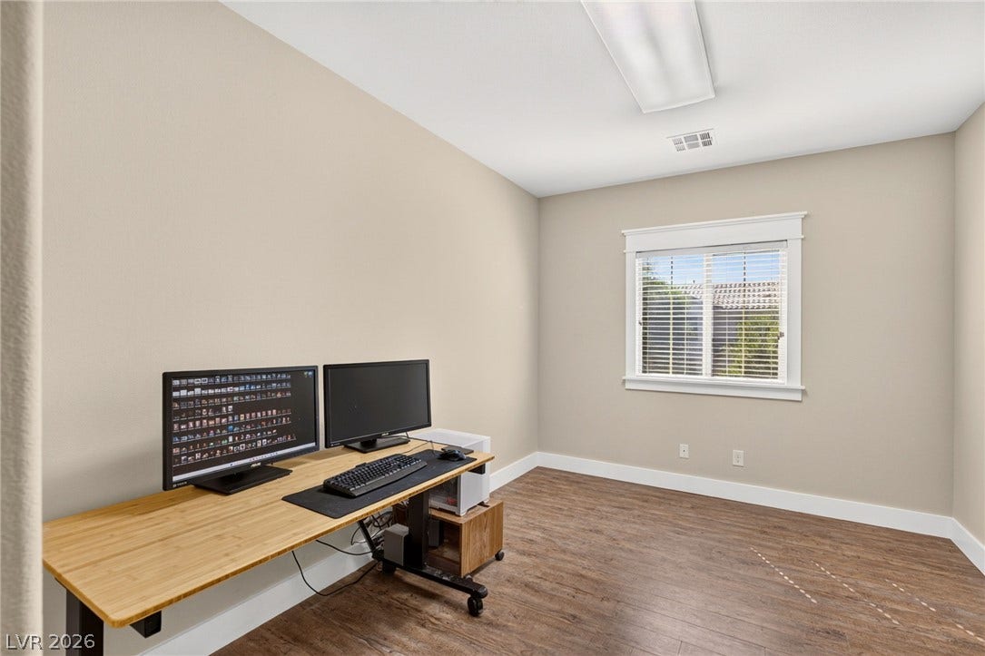 8112 Winterfell Place, Las Vegas, NV 89166 Rich wood-inspired flooring and a classic window frame establish a serene workspace environment.