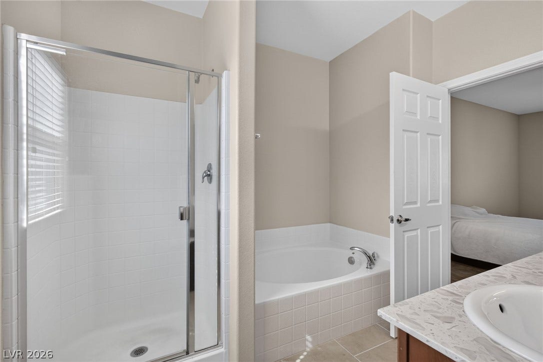 8112 Winterfell Place, Las Vegas, NV 89166 A glass-enclosed walk-in shower stands adjacent to a deep soaking tub.