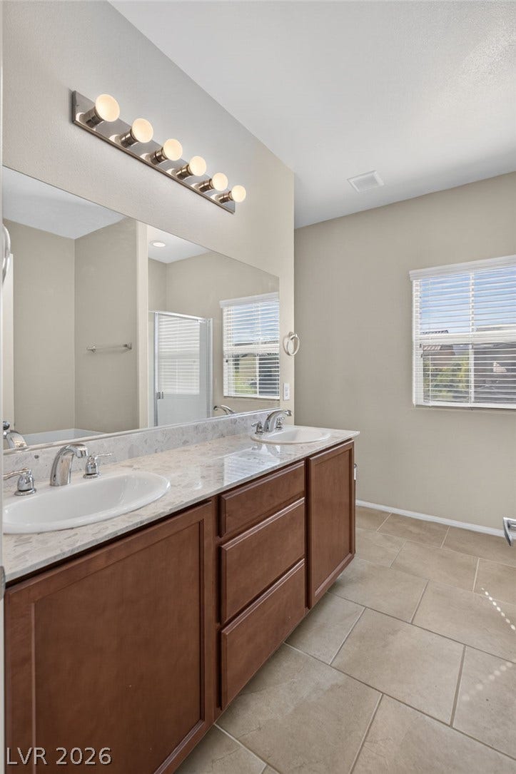 8112 Winterfell Place, Las Vegas, NV 89166 Clean tile flooring and a double vanity define this spacious bathroom.