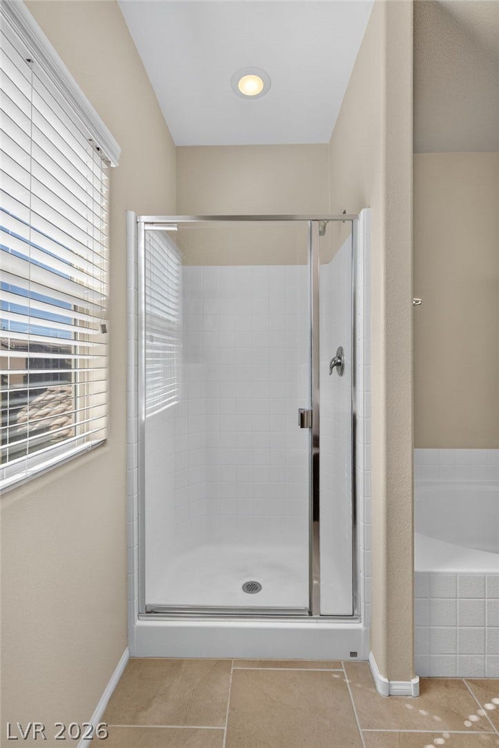 8112 Winterfell Place, Las Vegas, NV 89166 A glass-enclosed walk-in shower stands adjacent to a tiled soaking tub alcove.