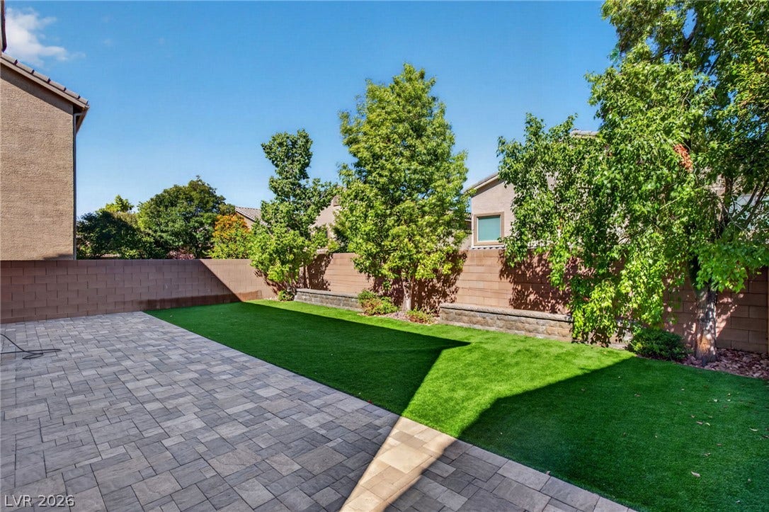 8112 Winterfell Place, Las Vegas, NV 89166 An inviting backyard features a pristine paver patio alongside manicured artificial turf and privacy fencing.