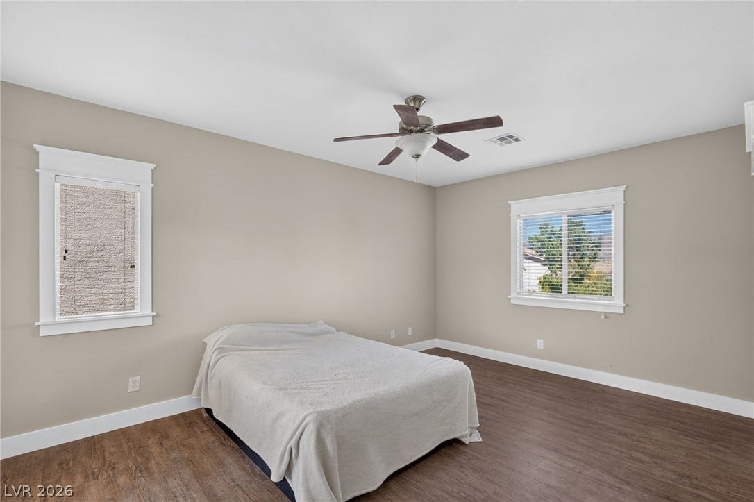 8112 Winterfell Place, Las Vegas, NV 89166 Rich wood-look flooring and classic window casings define this serene bedroom space.