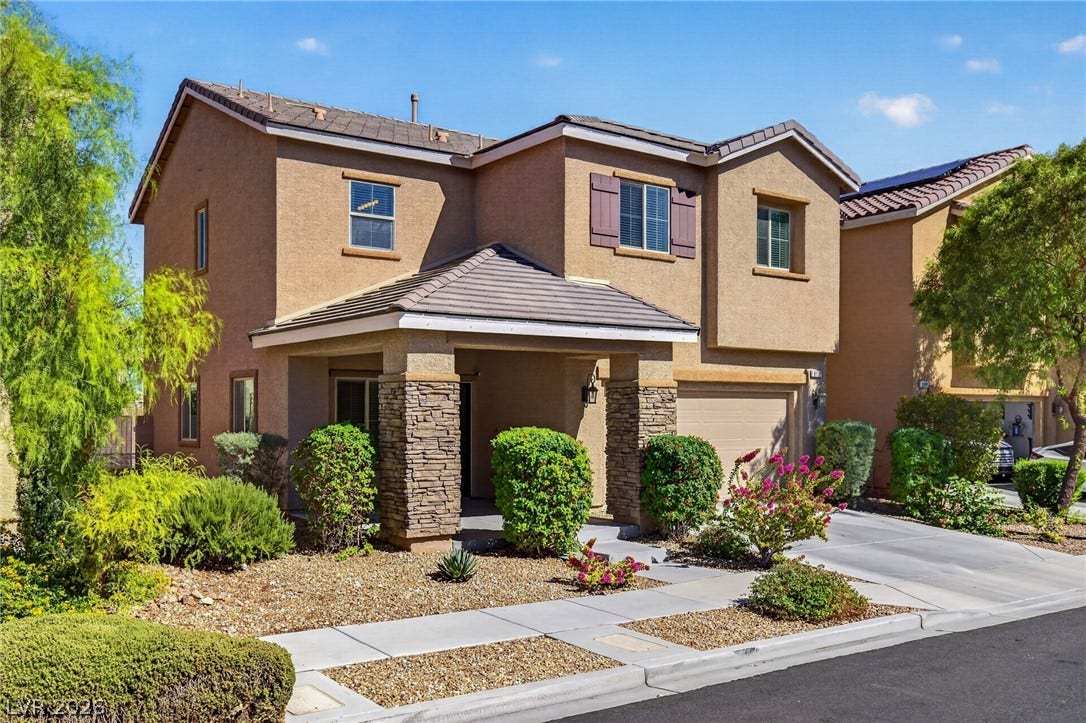 8112 Winterfell Place, Las Vegas, NV 89166 A classic two-story exterior features stone-accented pillars, a covered entryway, and neatly landscaped grounds.