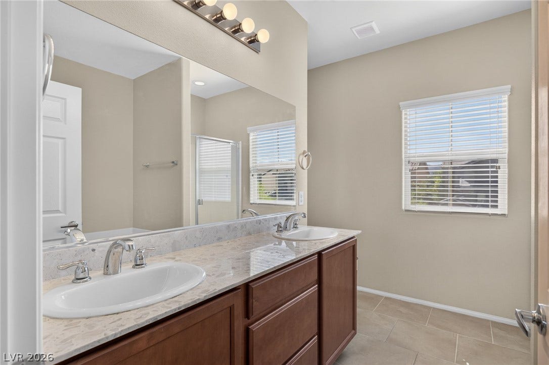 8112 Winterfell Place, Las Vegas, NV 89166 Double sinks accent a spacious vanity beneath high ceilings and neutral tile flooring.