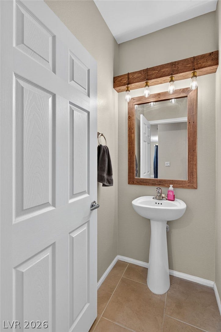 8112 Winterfell Place, Las Vegas, NV 89166 A classic pedestal sink sits beneath a wood-framed mirror in this cozy powder room.