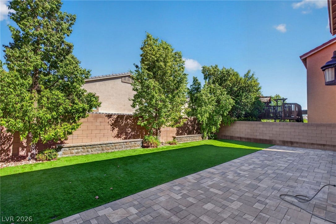 8112 Winterfell Place, Las Vegas, NV 89166 An inviting stone patio opens to a manicured green lawn enclosed by privacy fencing.