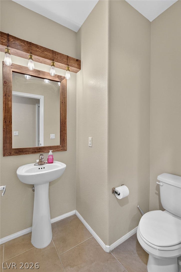 8112 Winterfell Place, Las Vegas, NV 89166 A classic pedestal sink sits beneath a wood-framed mirror in this neutral powder room.