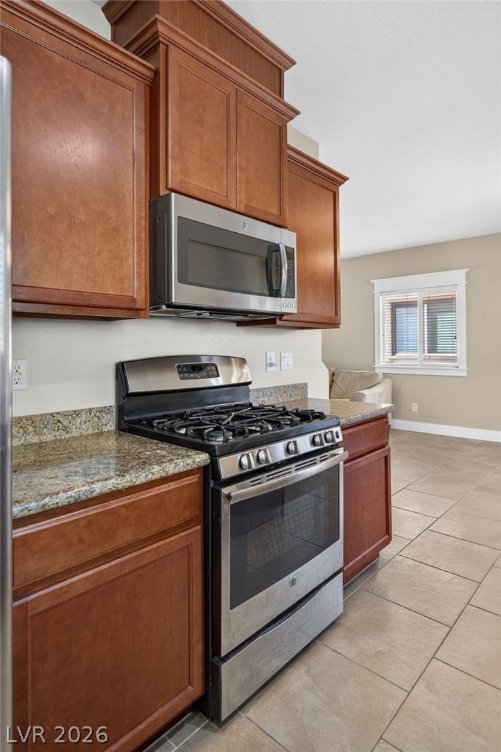 8112 Winterfell Place, Las Vegas, NV 89166 Rich wood cabinetry contrasts beautifully with granite countertops and stainless steel appliances.