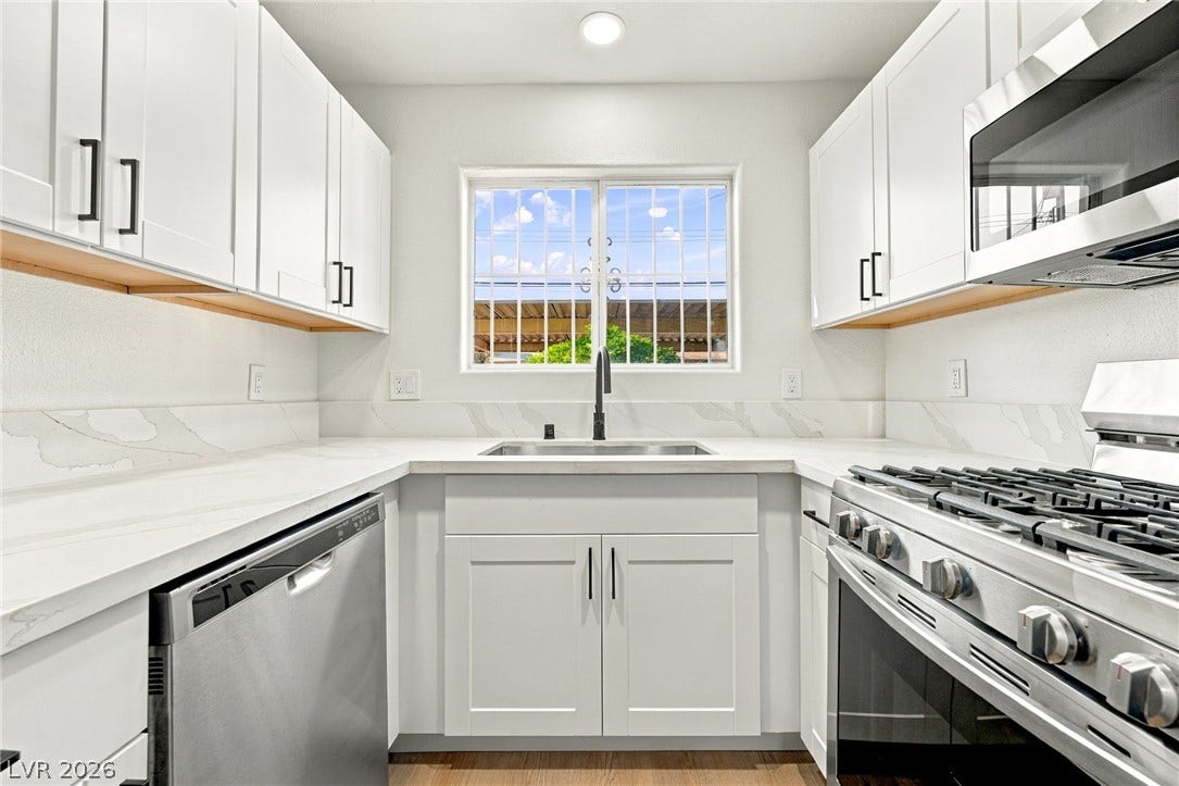 4500 W Lake Mead Boulevard, #102, Las Vegas, NV 89108 Sleek stone countertops and crisp white cabinetry frame a bright window in this kitchen.