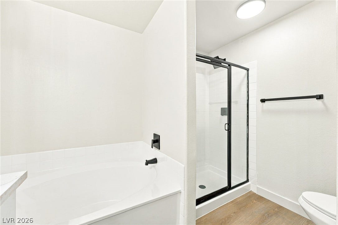 4500 W Lake Mead Boulevard, #102, Las Vegas, NV 89108 A modern bathroom features a deep soaking tub alongside a glass-enclosed walk-in shower.