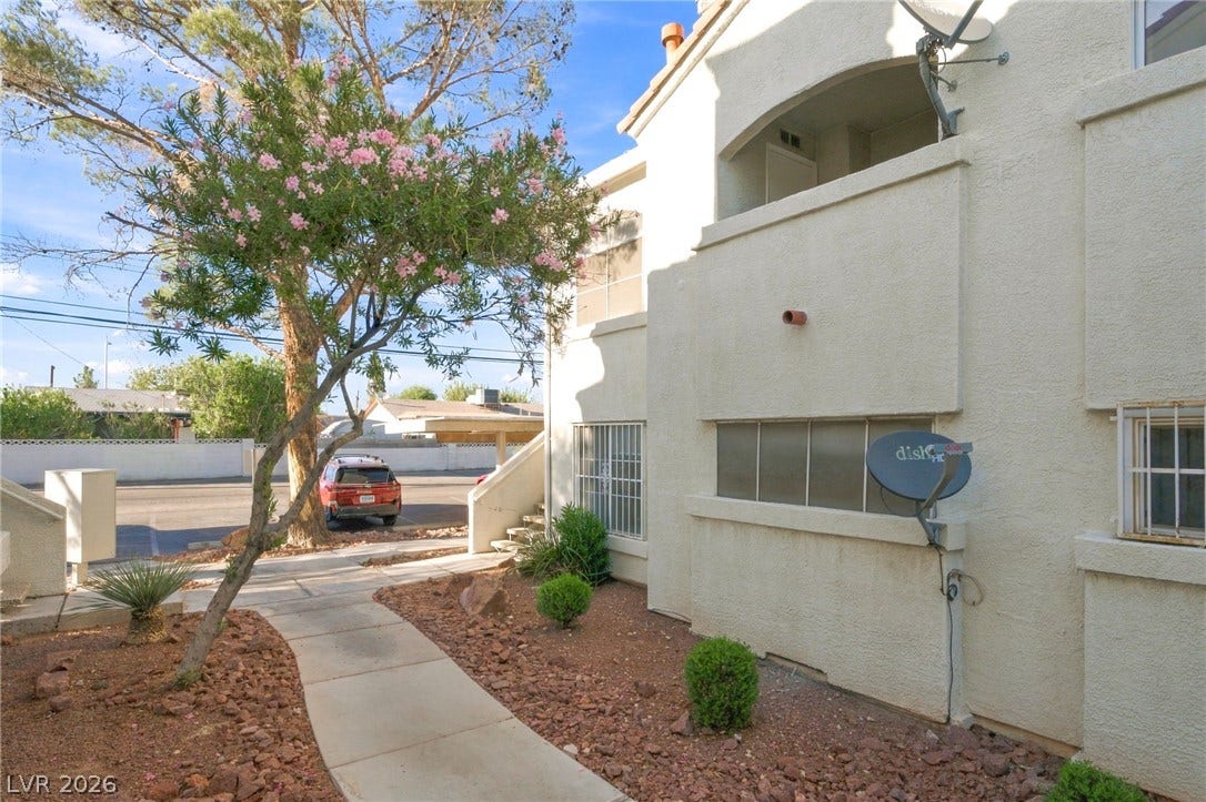 4500 W Lake Mead Boulevard, #102, Las Vegas, NV 89108 A paved walkway winds past desert landscaping toward the entrance of this multi-level stucco building.
