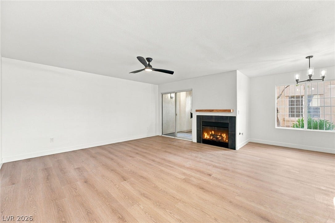 4500 W Lake Mead Boulevard, #102, Las Vegas, NV 89108 An inviting fireplace warms the living room characterized by light wood-style flooring and sliding glass doors.